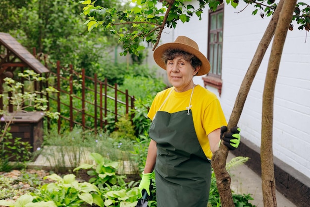 Retrato de uma jardineira sênior de chapéu trabalhando em seu quintal O conceito de jardinagem crescendo e cuidando de flores e plantas