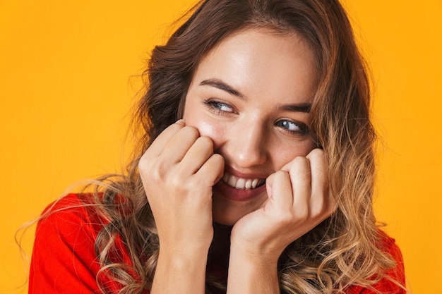 Foto retrato de uma jovem adorável alegre brincalhão isolado na parede amarela, posando