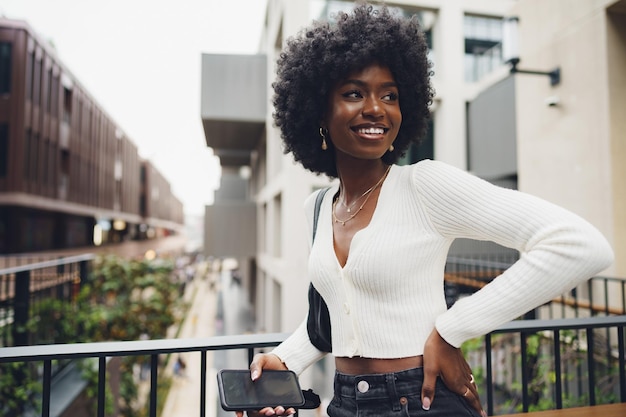 Retrato de uma jovem africana com penteado afro em pé na varanda e posando