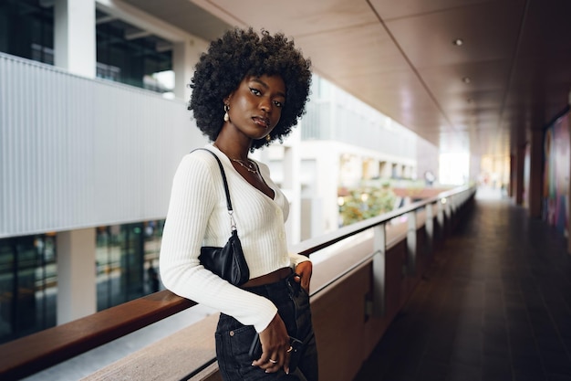 Retrato de uma jovem africana com penteado afro em pé na varanda e posando