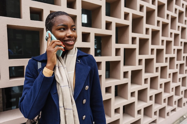 Retrato de uma jovem africana feliz falando com o celular na cidade