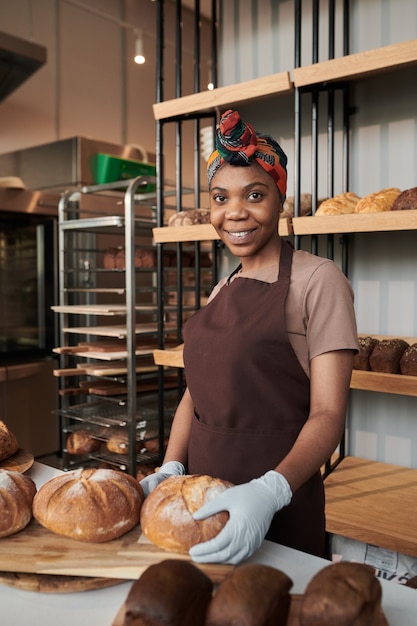 Retrato de uma jovem africana no proprietário sorrindo para a câmera enquanto assava o pão