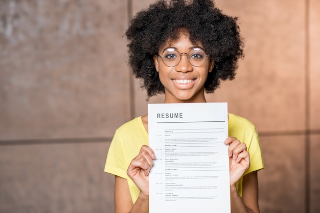 Retrato de uma jovem africana segurando o documento de currículo dentro de casa