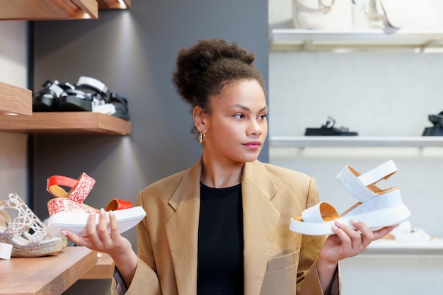 Retrato de uma jovem afro-americana escolhendo sapatos de verão em uma loja