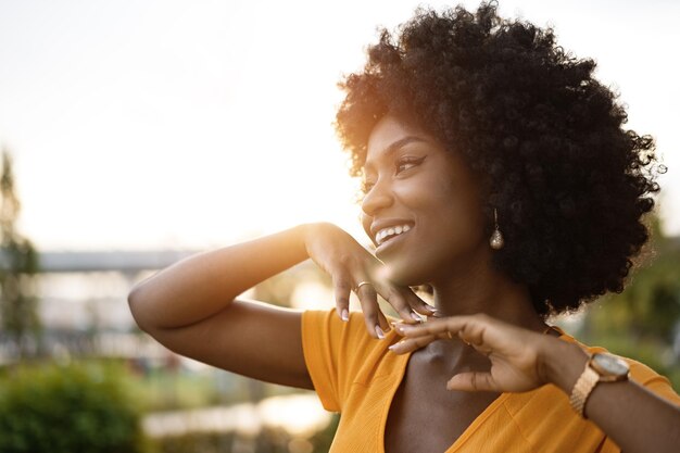 Retrato de uma jovem afro-americana sorrindo em pé na cidade