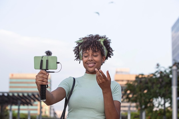 Retrato de uma jovem afro-americana transmitindo ao vivo em seu smartphone enquanto caminhava pelo espaço de cópia do conceito de jovem blogueiro da cidade