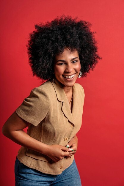 Foto retrato de uma jovem afro sorridente contra um fundo vermelho se divertindo
