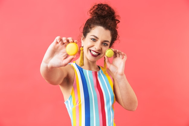 Foto retrato de uma jovem alegre com um vestido de pé isolado sobre um fundo vermelho.