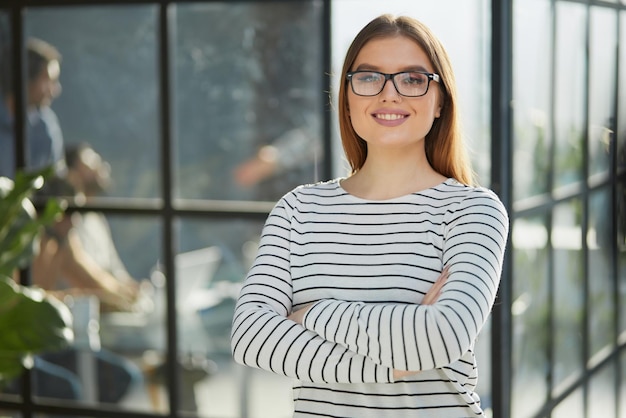 Retrato de uma jovem alegre em pé no escritório