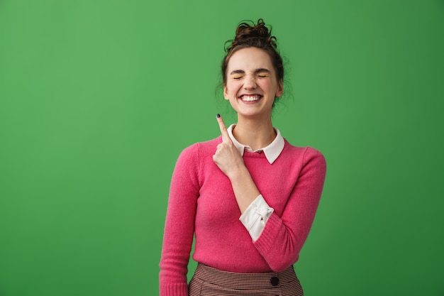 Foto retrato de uma jovem alegre isolada, apontando para o espaço da cópia