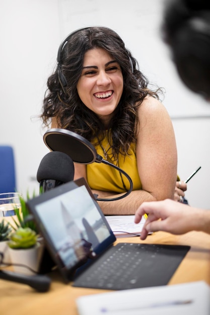 Retrato de uma jovem apresentadora de rádio ou podcaster caucasiana rindo durante a gravação de um programa