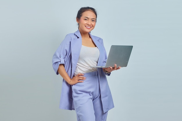 Retrato de uma jovem asiática alegre usando laptop e olhando para câmera isolada em fundo branco