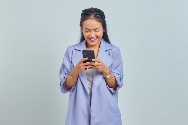 Retrato de uma jovem asiática alegre usando telefone celular isolado em fundo branco