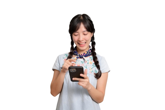 Retrato de uma jovem asiática bonita e feliz em um vestido jeans usando um smartphone em uma foto de estúdio de fundo branco