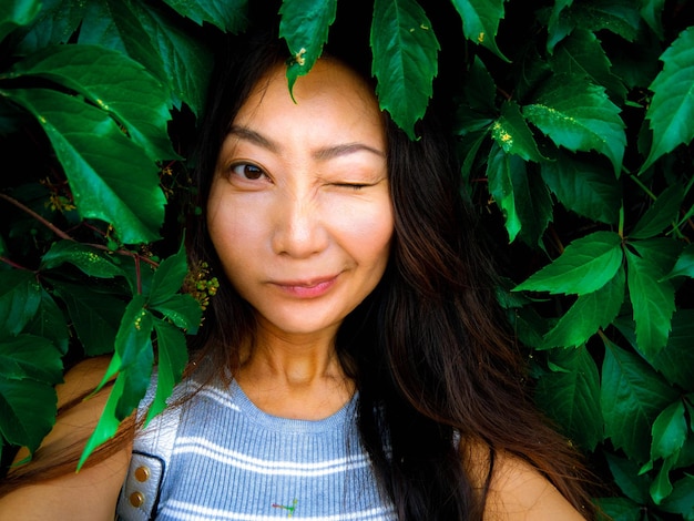 Foto retrato de uma jovem asiática com folhas verdes