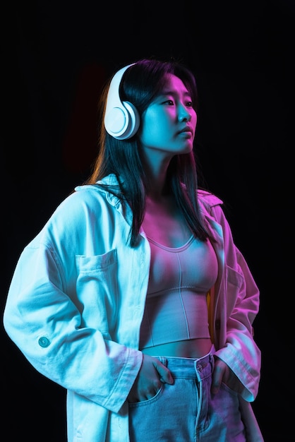 Retrato de uma jovem asiática em fundo de estúdio escuro em neon conceito de emoções humanas expressão facial anúncio de vendas de jovens