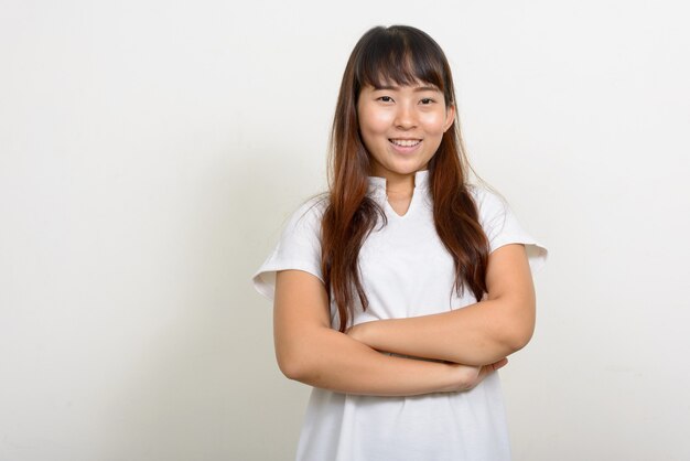 Retrato de uma jovem asiática feliz sorrindo com os braços cruzados