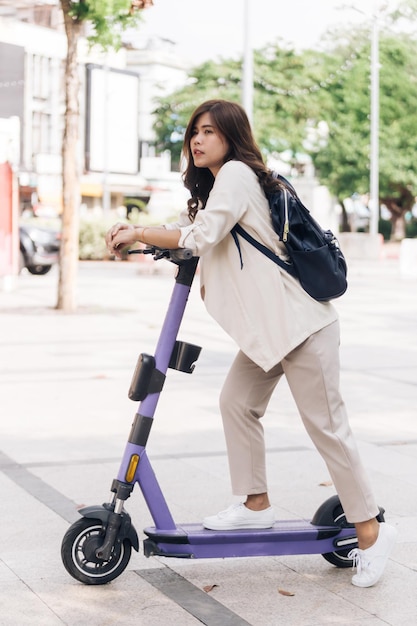 Retrato de uma jovem asiática montando uma scooter elétrica no parque