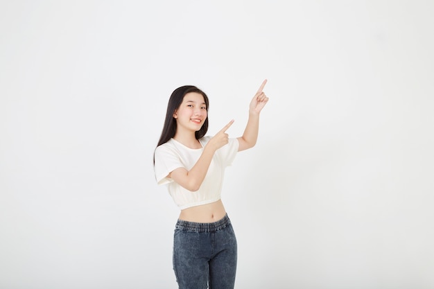 Retrato de uma jovem asiática sorridente com uma camiseta de verão apontando com um dedo para o espaço da cópia