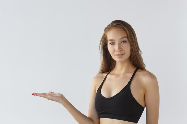 Retrato de uma jovem atleta em um fundo branco apontando motivação para esportes de treinamento