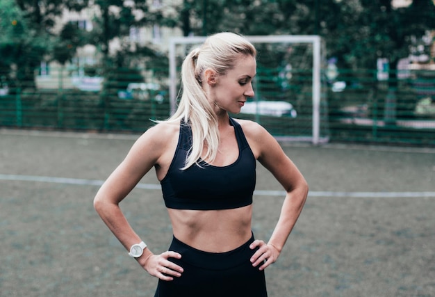 Foto retrato de uma jovem atleta feminina em roupas esportivas contra o pano de fundo de um estádio verde