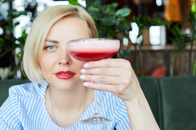 Retrato de uma jovem atraente bebendo coquetel no café interior Linda loira relaxando no bar e bebendo um coquetel