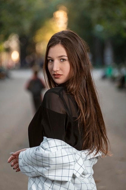 Retrato de uma jovem atraente com cabelos longos no fundo do parque Olhar de cabelos negros