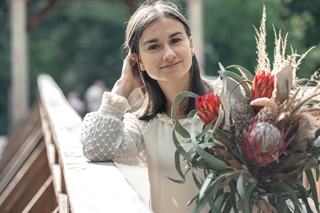 Retrato de uma jovem atraente com um buquê de flores exóticas