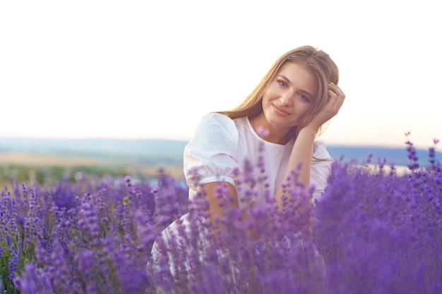 Retrato de uma jovem atraente em um campo de lavanda ao pôr do sol