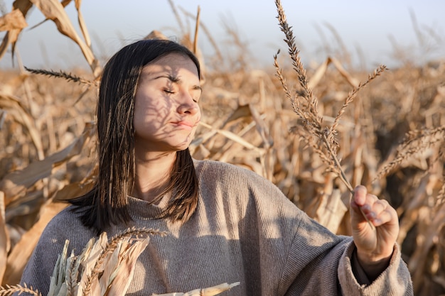 Retrato de uma jovem atraente em um campo de milho ao pôr do sol.