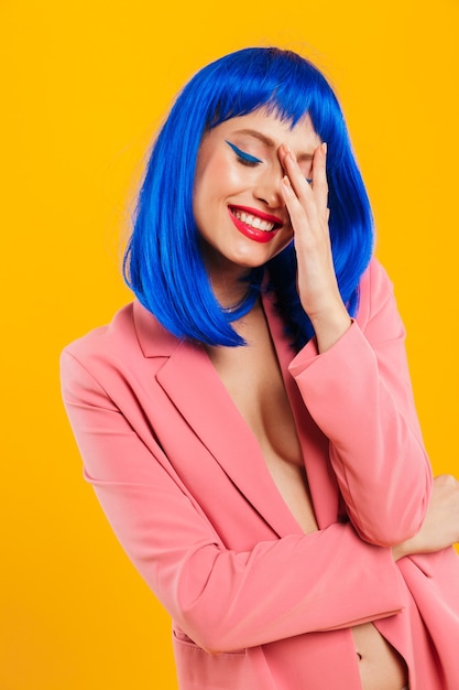 Retrato de uma jovem atraente, feliz e descolada com cabelo azul, vestindo uma roupa casual em pé isolado sobre a parede amarela