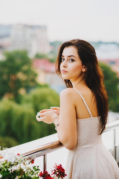 Retrato de uma jovem atraente lá fora na varanda com flores