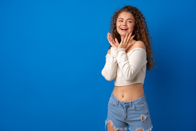 Retrato de uma jovem atraente mulher de cabelos cacheados contra um fundo azul.