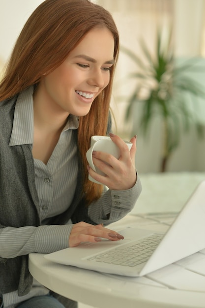 Retrato de uma jovem atraente se comunicando através de um laptop