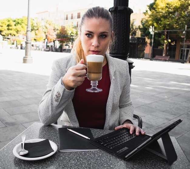 Foto retrato de uma jovem bebendo café na cidade