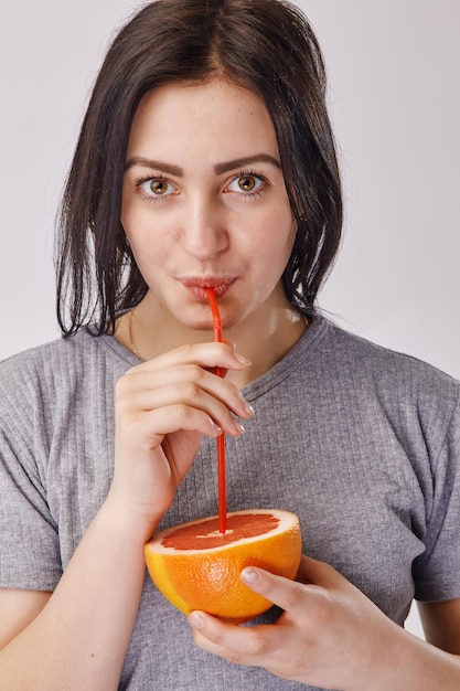 Retrato de uma jovem bebendo um suco de laranja com um canudo