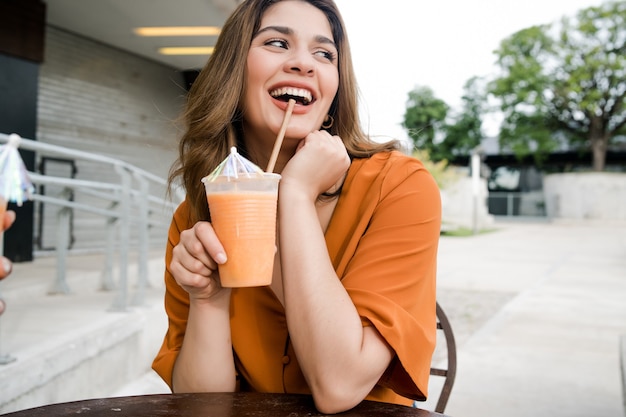 Retrato de uma jovem bebendo um suco fresco em uma cafeteria ao ar livre