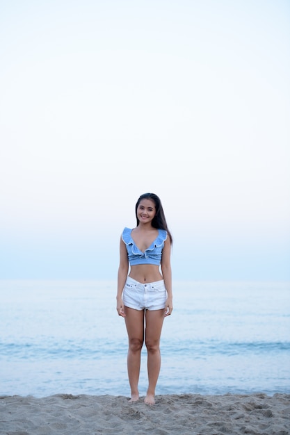 Retrato de uma jovem bela turista asiática relaxando na praia