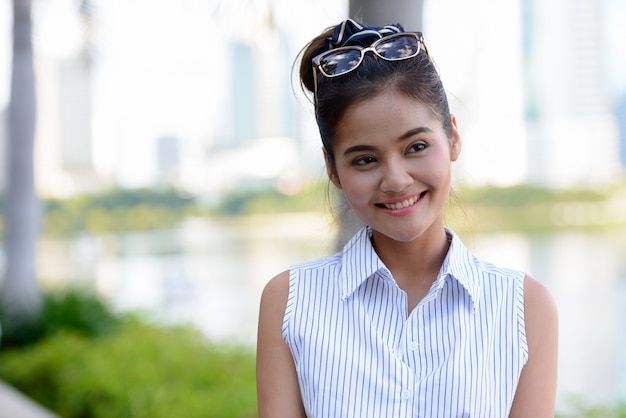 Retrato de uma jovem bela turista asiática relaxando no parque ao ar livre