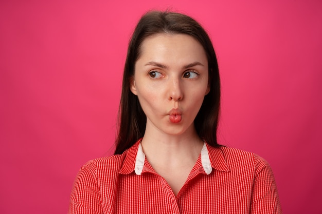 Foto retrato de uma jovem bonita com as bochechas contra o fundo rosa