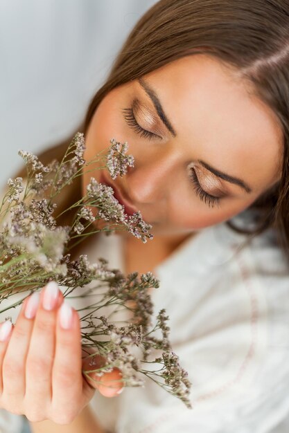 Foto retrato de uma jovem bonita com cabelo comprido em fundo branco com flores secas primavera