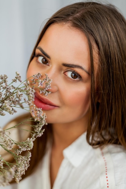 Retrato de uma jovem bonita com cabelo comprido em fundo branco com flores secas Primavera