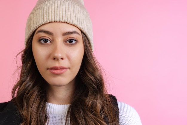 Retrato de uma jovem bonita com chapéu, olhando para a câmera, posando, isolada em rosa.