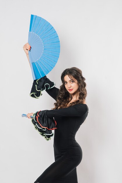 Retrato de uma jovem bonita dançando flamenco com ventilador no estúdio