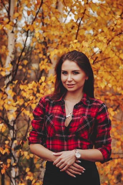 Retrato de uma jovem bonita de aparência eslava no casual wear no outono, na zona rural no contexto de um parque de outono. Mulher bonita andando na floresta no outono dourado. Copie o espaço