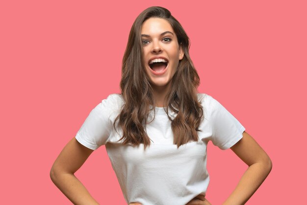 Retrato de uma jovem bonita e alegre menina sorrindo olhando para a câmera em fundo rosa