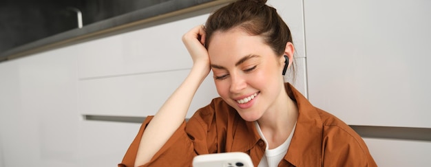 Foto retrato de uma jovem bonita e feliz ouvindo música em fones de ouvido sem fio usando um smartphone