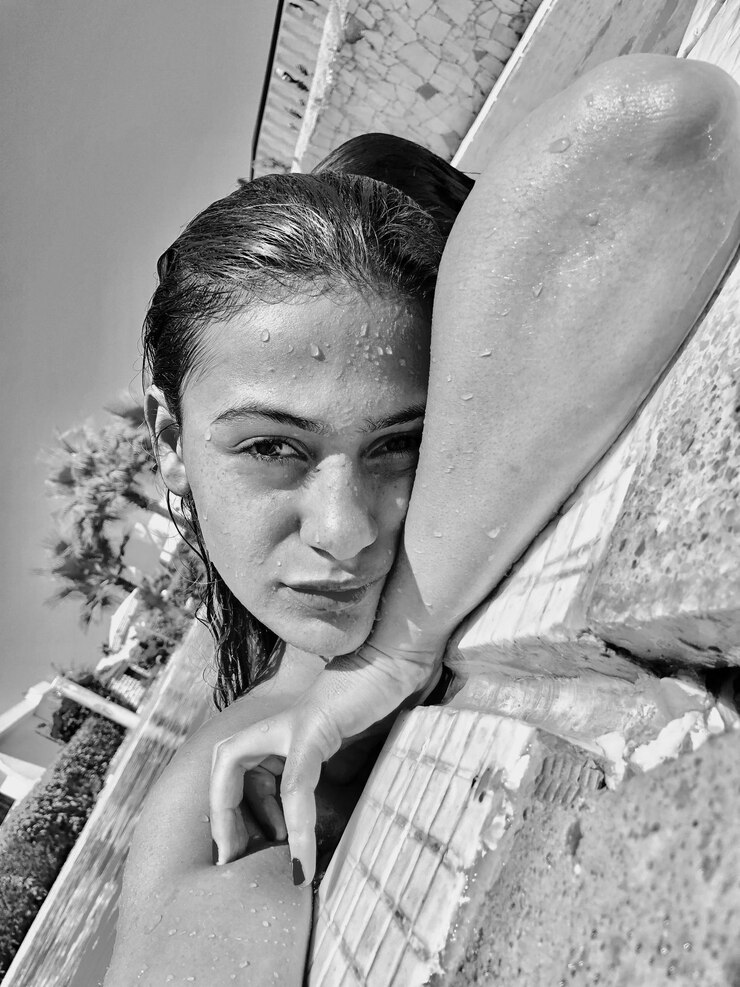 Foto retrato de uma jovem bonita e molhada relaxando à beira da piscina contra o céu