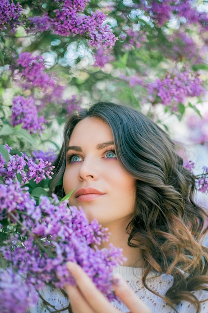 Retrato de uma jovem bonita em um parque florido lilás.