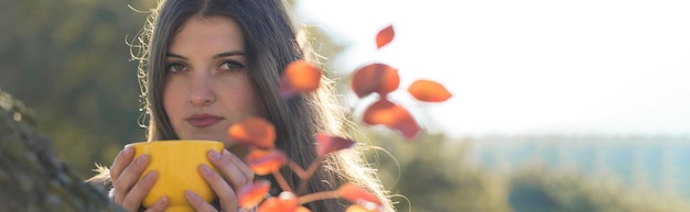 Foto retrato de uma jovem bonita em um suéter de malha elegante em pé na floresta dourada do outono no dia ensolarado